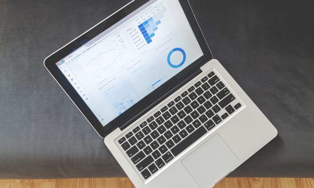 Overhead view of a laptop showing data visualizations and charts on its screen.