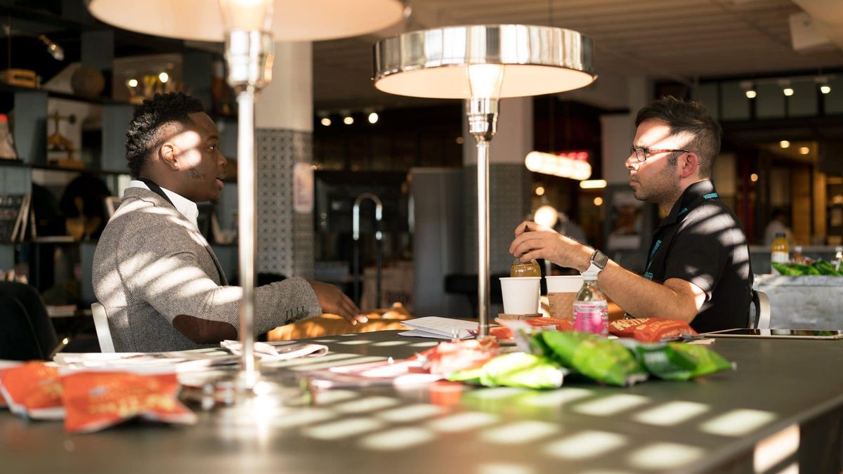 Two men engaged in discussion around a table in a modern office environment.