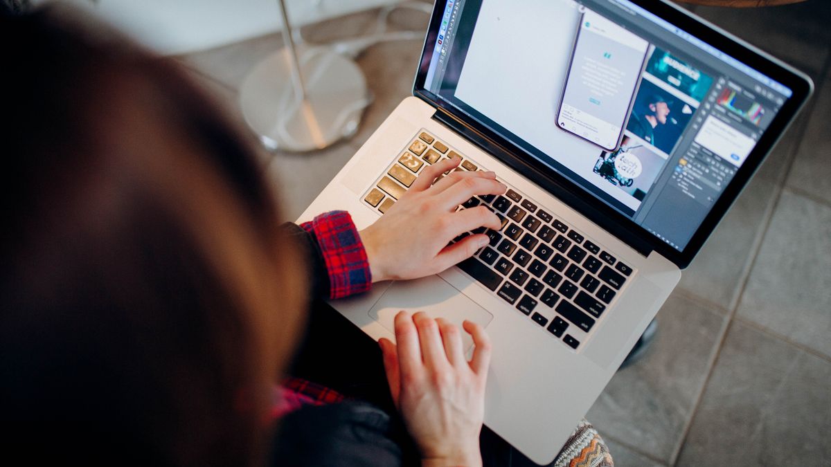 Close-up of a person working on a laptop with graphic design software.