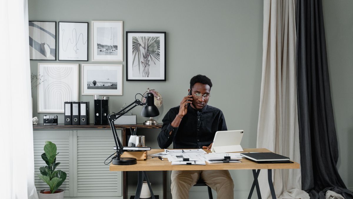 Businessman talking on phone while working in stylish office with tablet and documents.