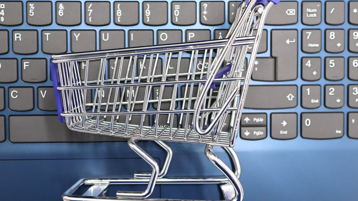 A miniature shopping cart placed on a laptop keyboard symbolizing online shopping and e-commerce.