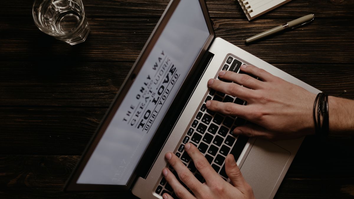 Hands on a laptop with an inspirational quote displayed on the screen, shot from above.
