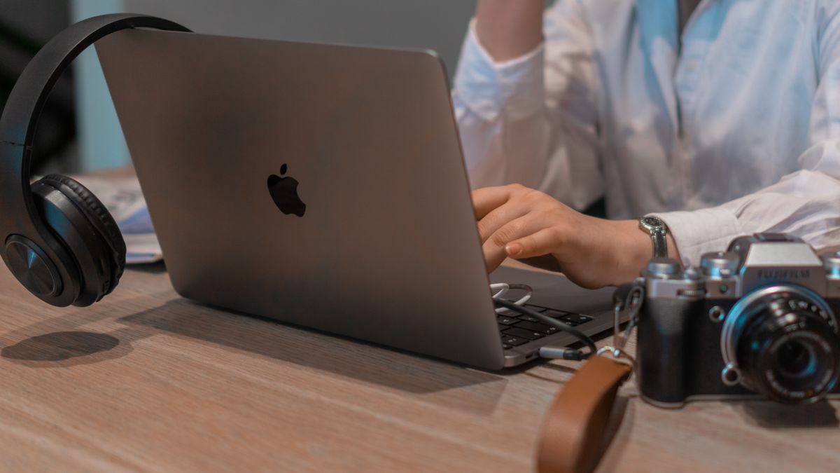 Close-up of a person working remotely with a laptop, headphones, and camera. Ideal for tech and lifestyle themes.