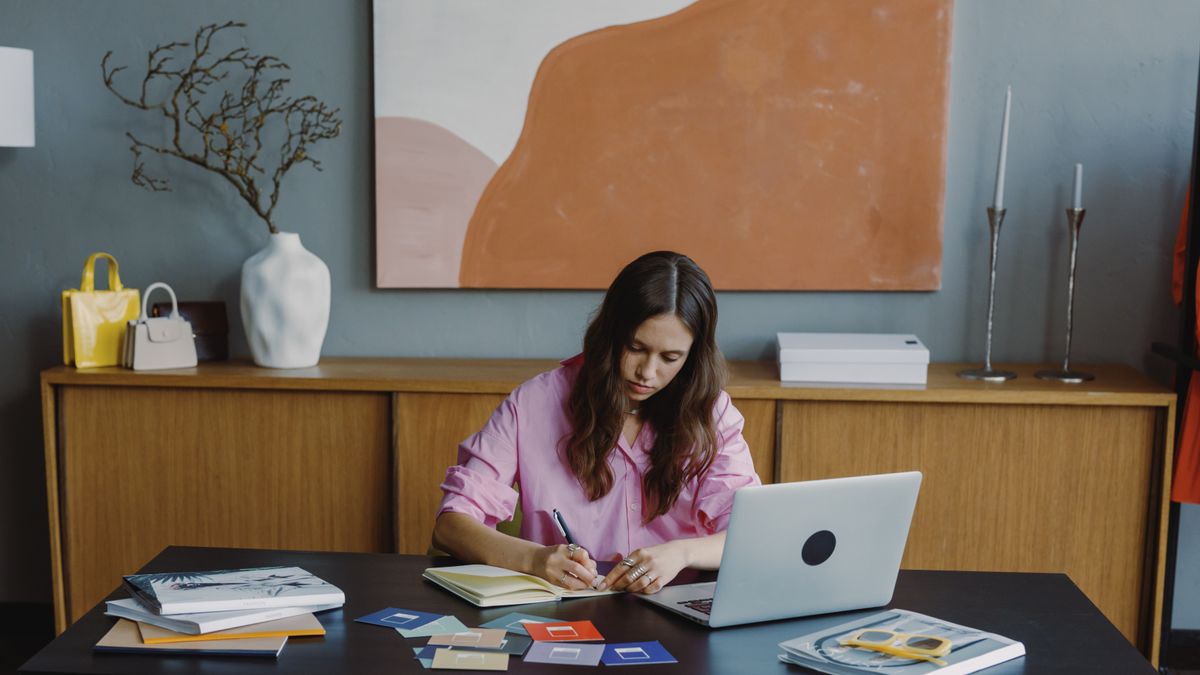 Woman working remotely at home office on a design project with laptop and color swatches.