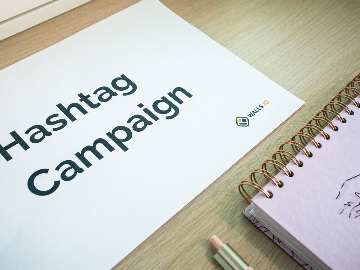 A clean office desk setup featuring hashtag campaign marketing materials and a planner.